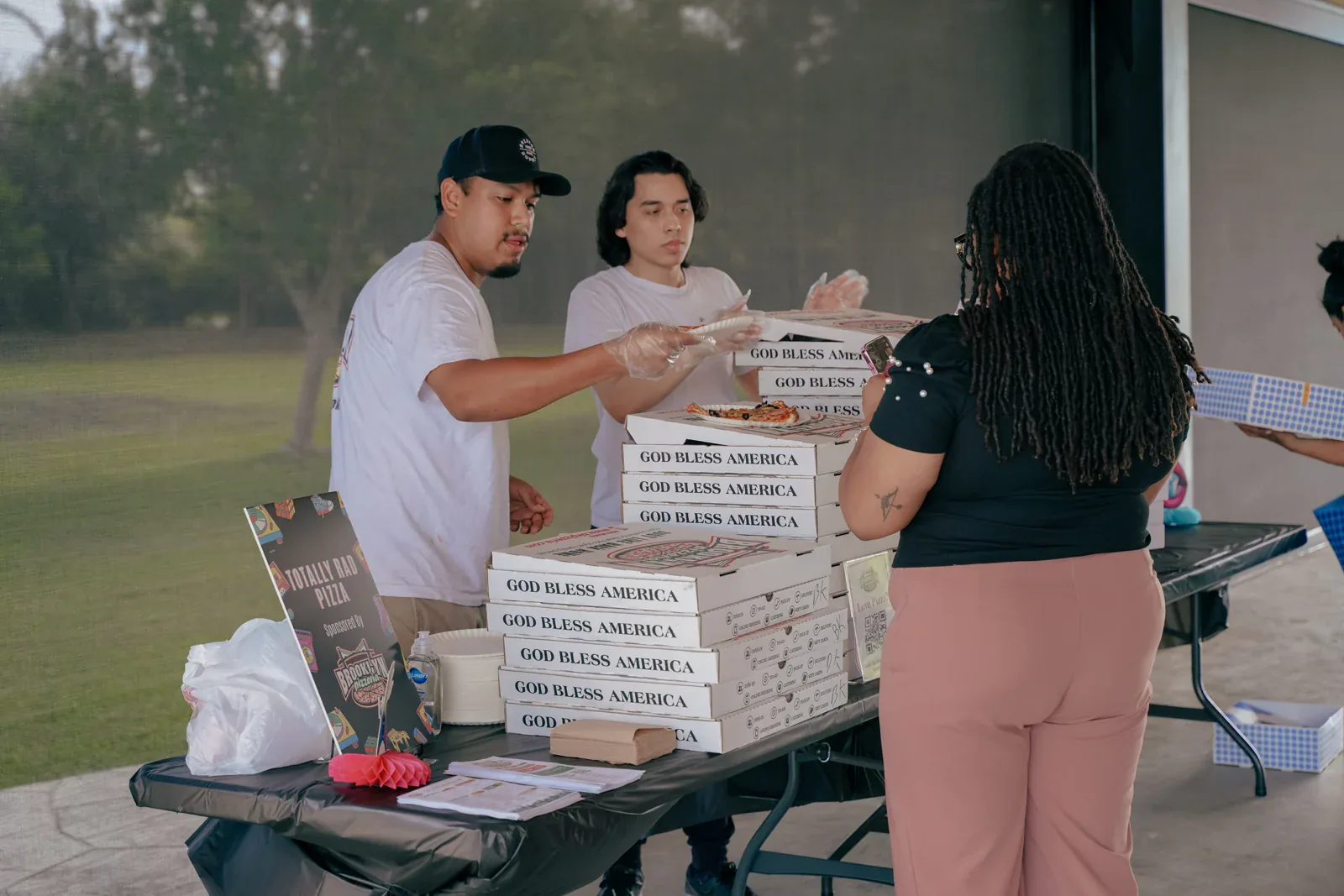 The Brooklyn Pizzeria team serving pizza to neighbors