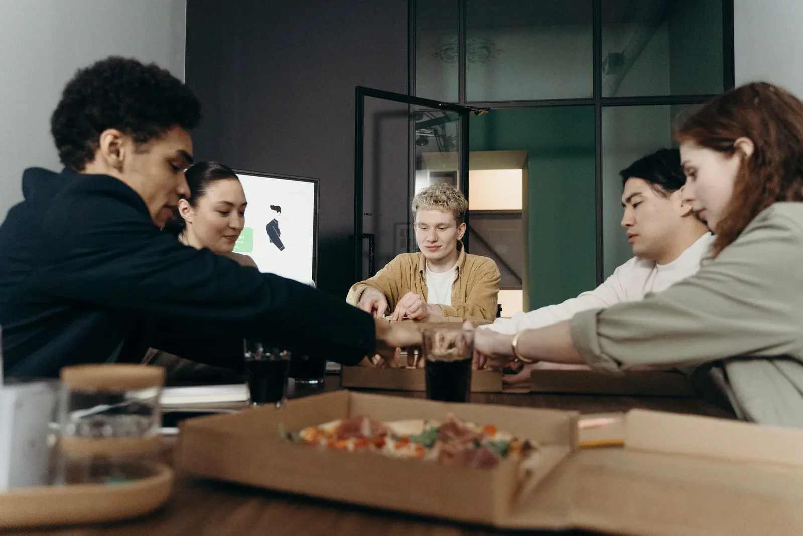 Colleagues sharing pizza around an office table