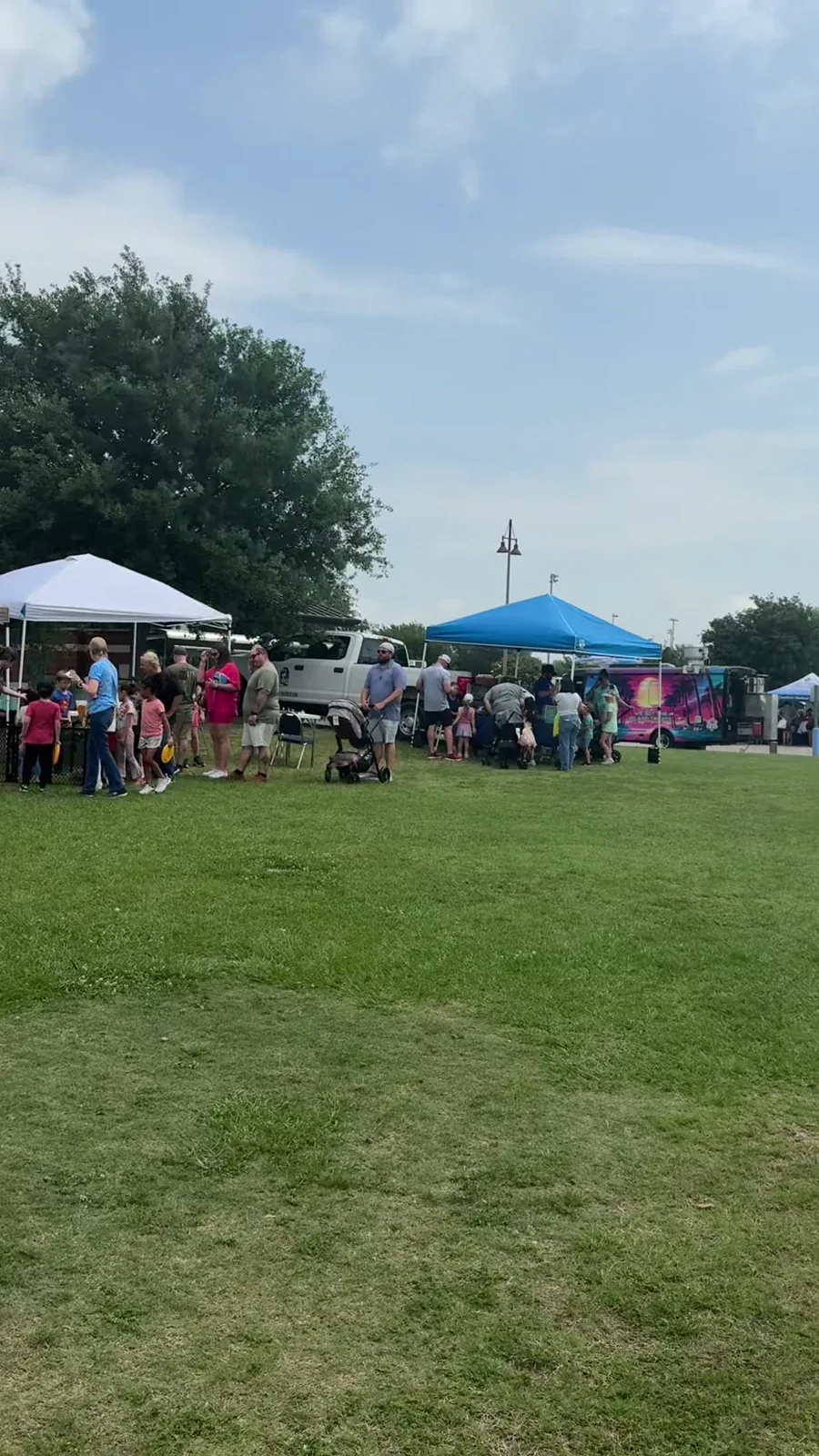 Neighbors gathered on a lawn among tents at a local community event