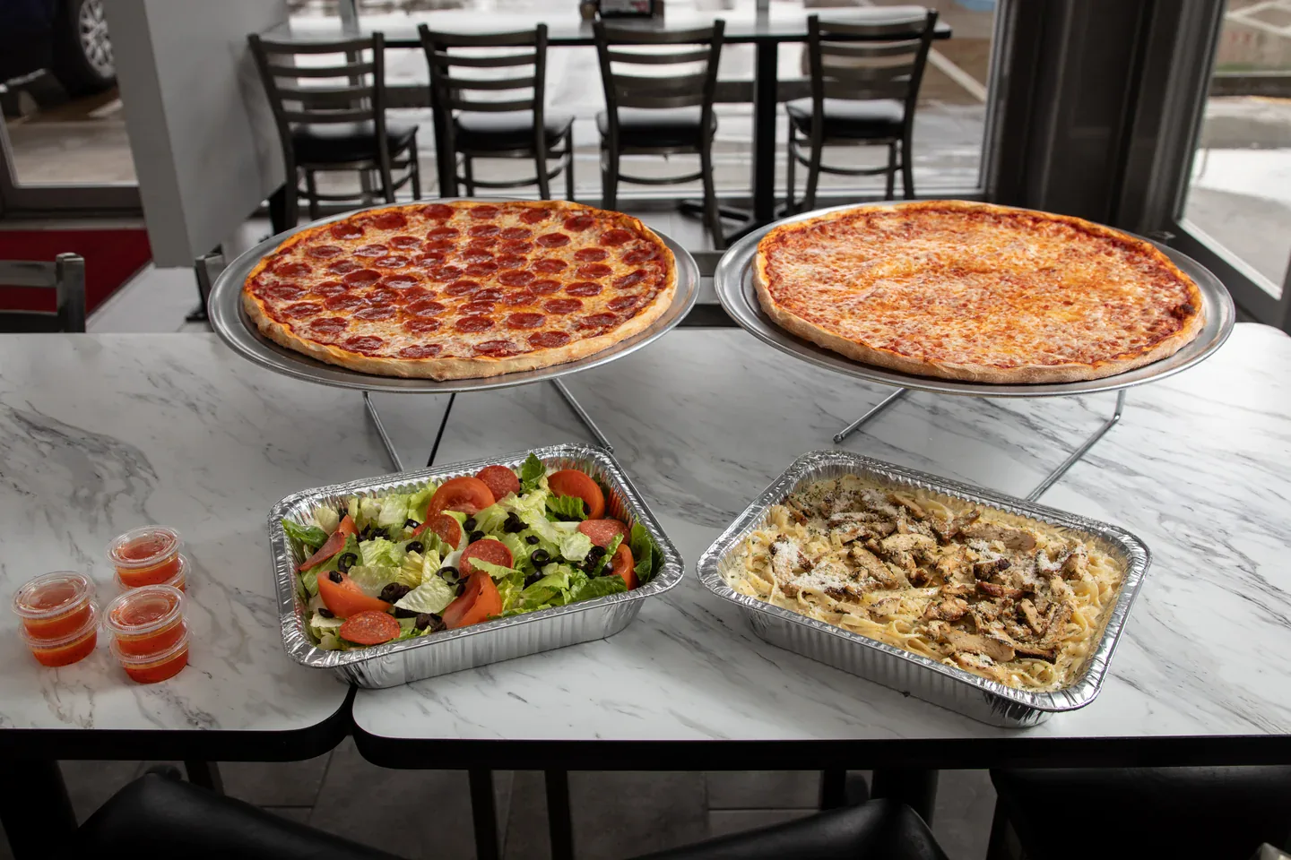 Pizza, pasta and salad trays ready for a Brooklyn Pizzeria gathering