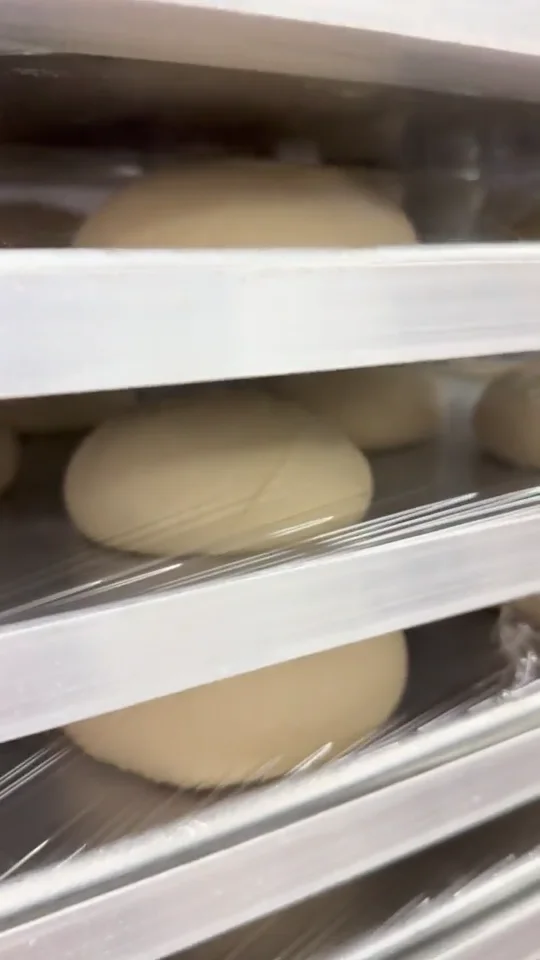 Fresh pizza dough resting in trays in the Brooklyn Pizzeria kitchen